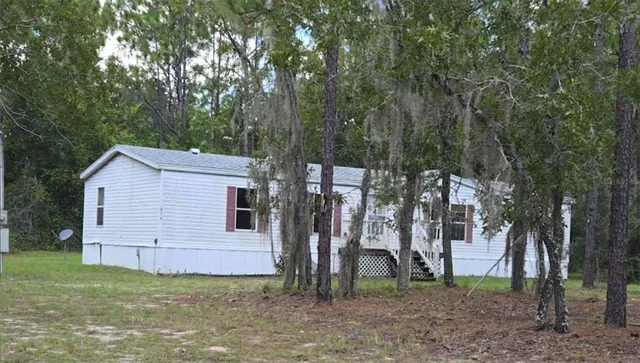 a view of a backyard with large trees and a barn