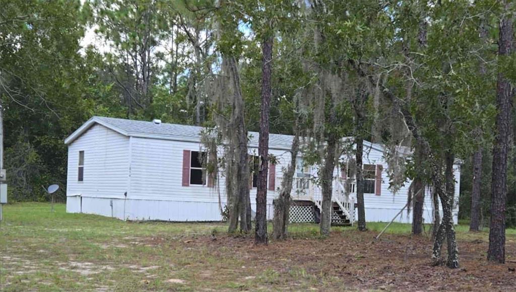a view of a backyard with large trees and a barn