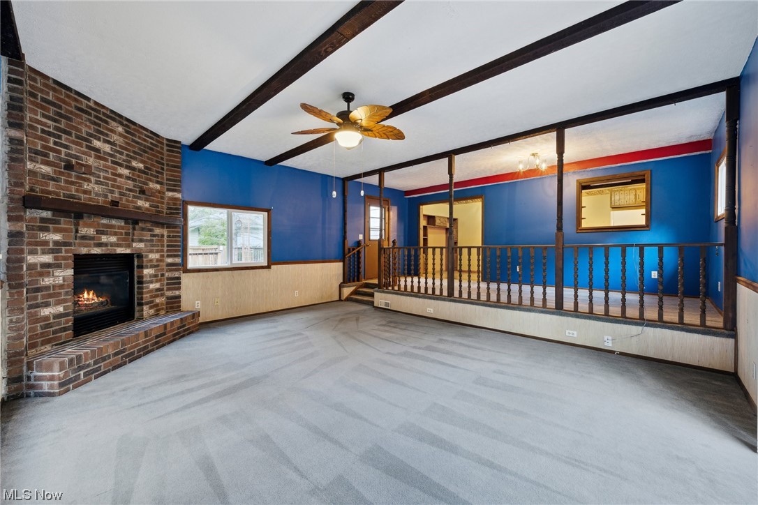 2715 Douglas Road Ashtabula, OH 44004 - Photo 11 of 34 Carpeted living room featuring brick wall, beamed ceiling, a fireplace, and ceiling fan