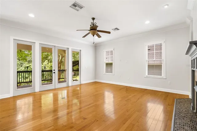 a view of an empty room with a window and wooden floor