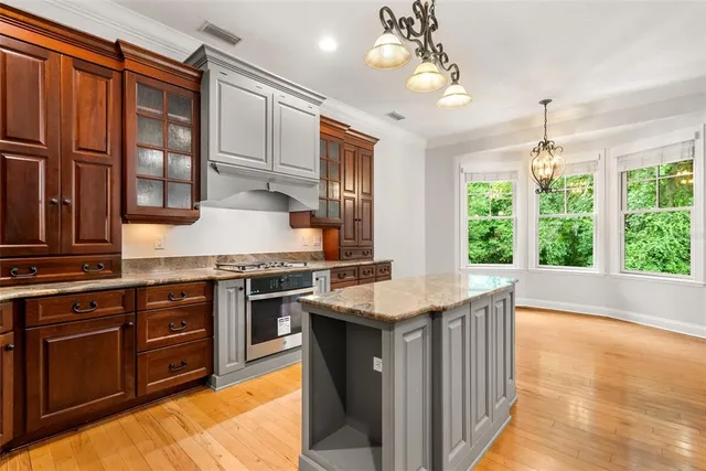a kitchen with stainless steel appliances kitchen island granite countertop a stove top oven and refrigerator