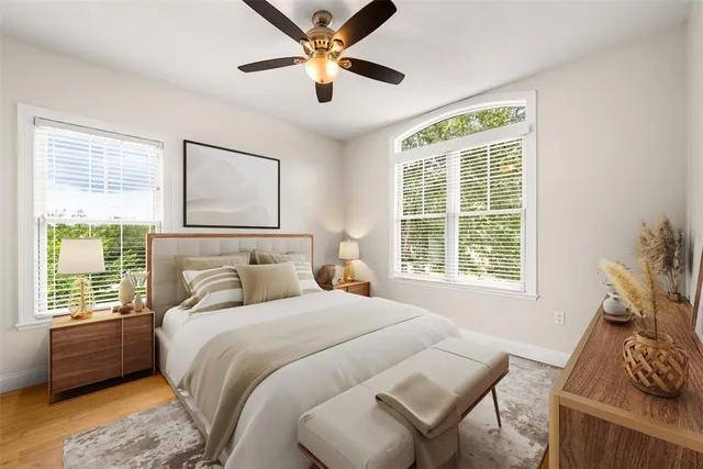 a view of a bedroom with wooden floor and a ceiling fan