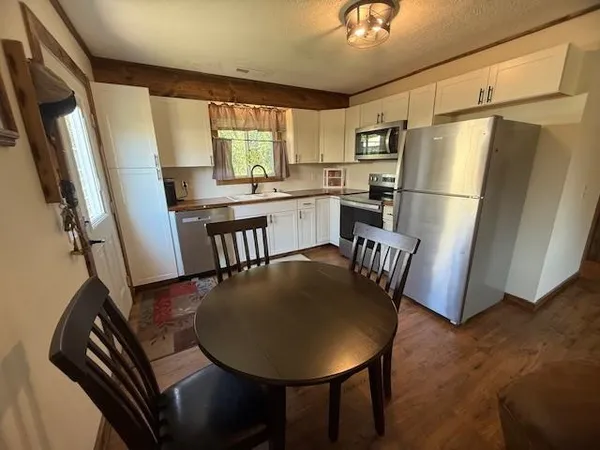 a kitchen with stainless steel appliances granite countertop a dining table chairs a refrigerator a stove a microwave and dining table