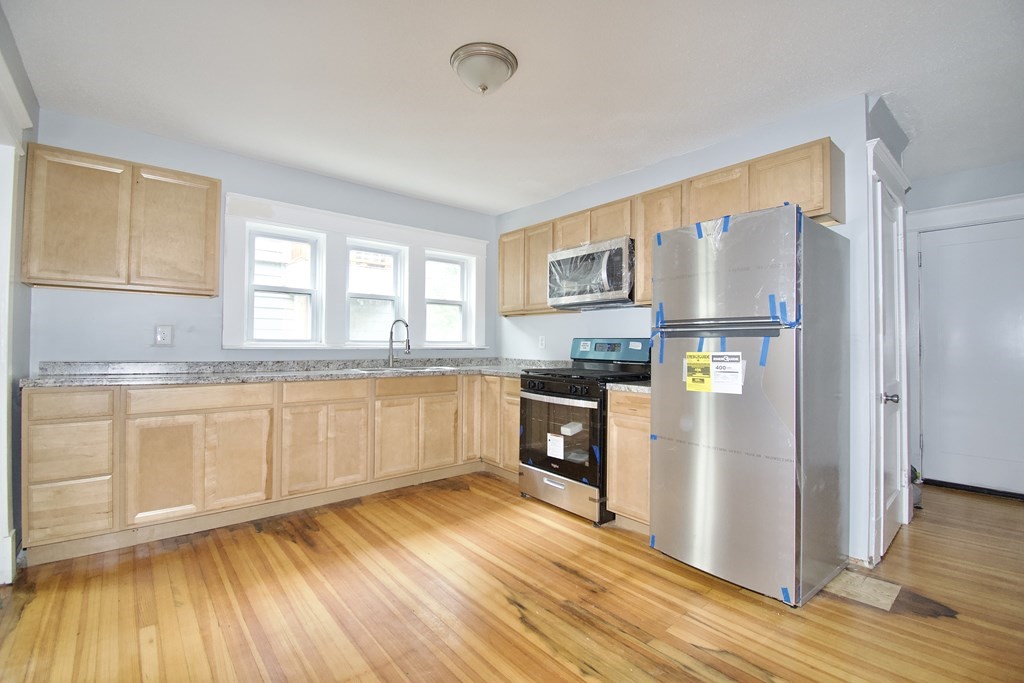 80-82 Silver Street Springfield, MA 01107 - Photo 26 of 31 a kitchen with granite countertop a refrigerator a sink dishwasher stove and wooden cabinets