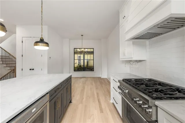 a large kitchen with stainless steel appliances a large counter top a stove and a refrigerator