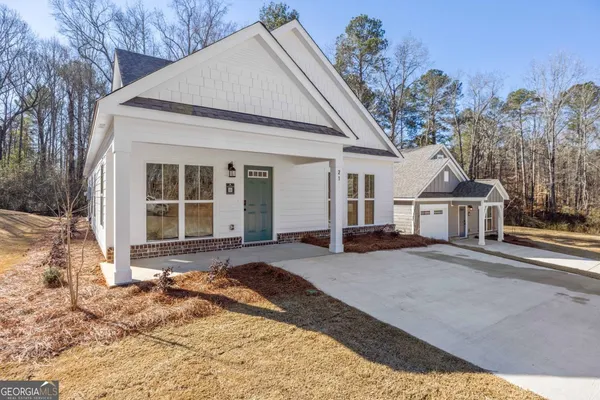 a view of a house with a yard and large tree