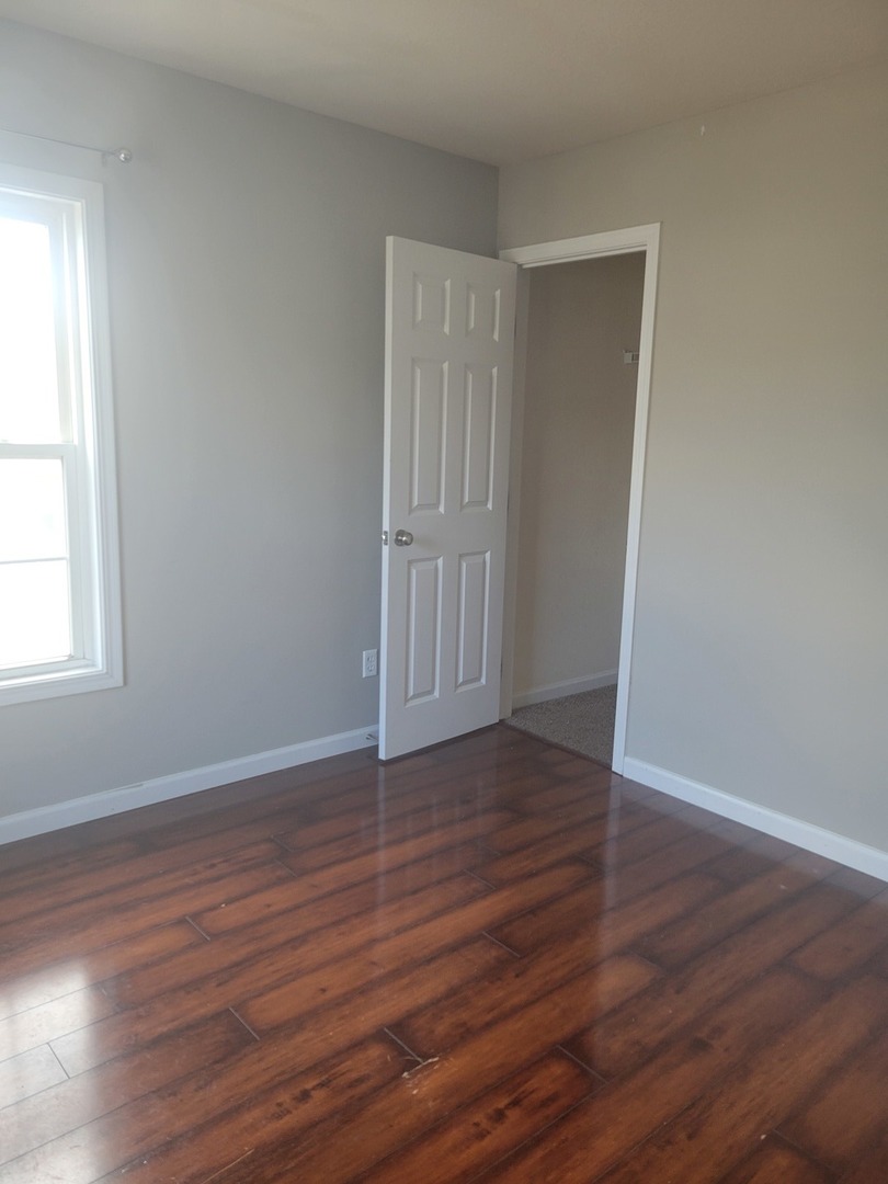 3704 Balcary Bay, Unit 3704 Champaign, IL 61822 - Photo 7 of 15 a view of an empty room with wooden floor and a window