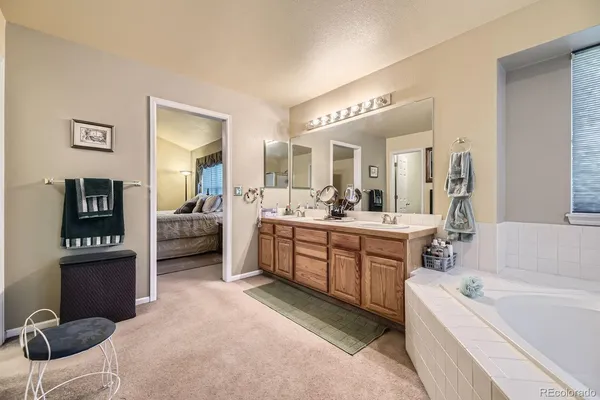 a large white bathroom with a double vanity sink a mirror and a bathtub