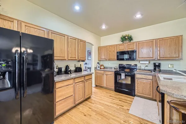 a kitchen with granite countertop a stove top oven a sink dishwasher and a refrigerator with wooden floor