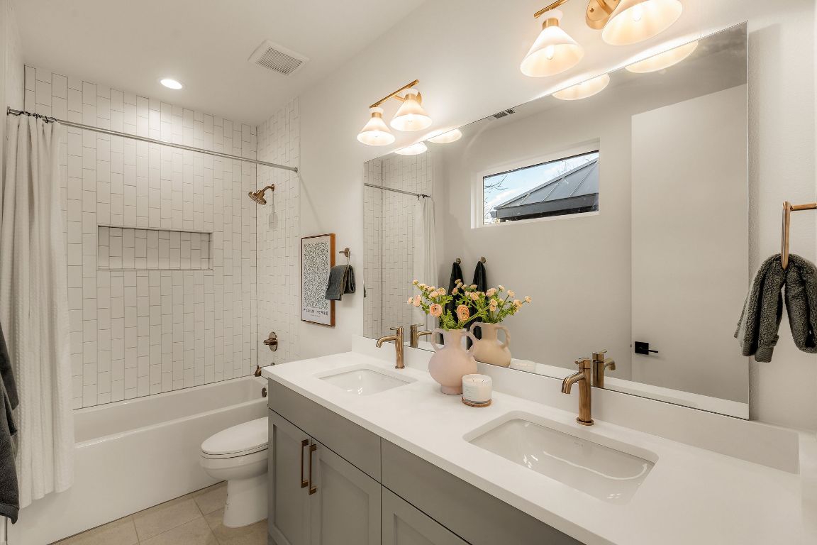 1301 Ruth Avenue Austin, TX 78757 - Photo 14 of 21 Full bath with double vanity, shower / bath combo with shower curtain, light tile patterned floors, and recessed lighting