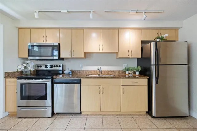 a kitchen with granite countertop a refrigerator stove and microwave