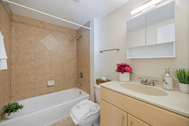 a bathroom with a sink vanity granite tub shower and a toilet