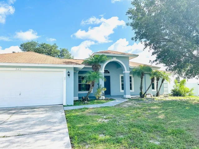 a view of a house with yard and large trees