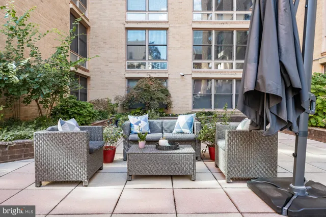 a view of a patio with couches table and chairs under an umbrella with a fire pit