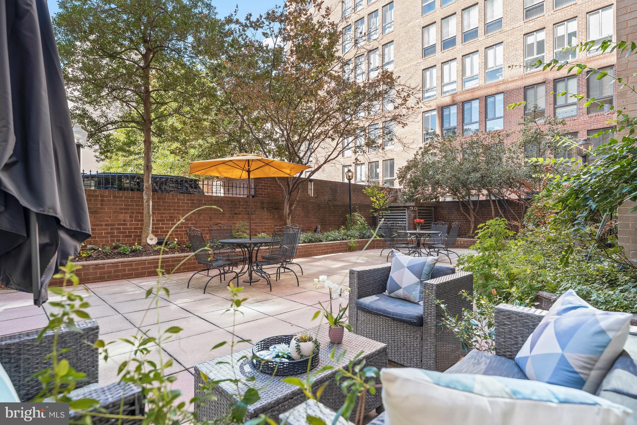 1260 21st Street Northwest, Unit 107 Washington, DC 20036 - Photo 18 of 21 a view of a patio with couches table and chairs under an umbrella with a fire pit