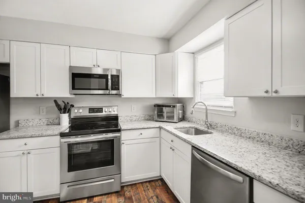 a kitchen with stainless steel appliances granite countertop white cabinets a sink and a stove