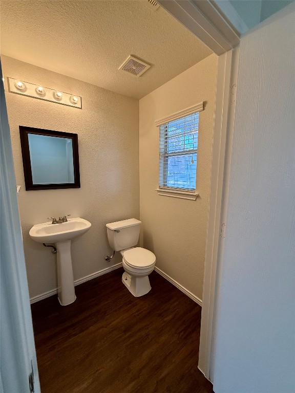 18304 Belfry Pass Manor, TX 78653 - Photo 6 of 26 Half bathroom featuring dark wood finished floors and a textured ceiling