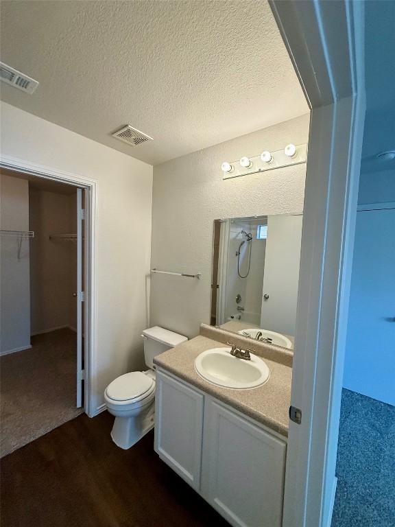 18304 Belfry Pass Manor, TX 78653 - Photo 9 of 26 Bathroom with a walk in closet, vanity, a textured ceiling, dark wood finished floors, and shower / bathtub combination