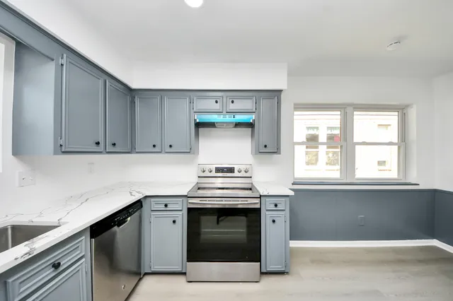 a kitchen with granite countertop white cabinets and stainless steel appliances
