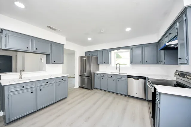 a kitchen with granite countertop a sink stove top oven and cabinets