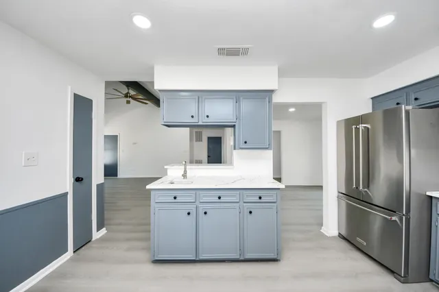 a kitchen with kitchen island stainless steel appliances a sink and a refrigerator