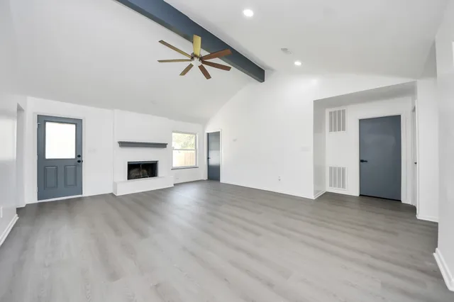 an empty room with wooden floor fireplace and windows