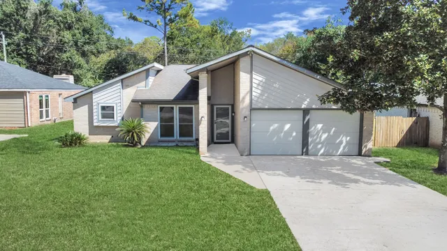 a view of a house with a yard plants and large tree