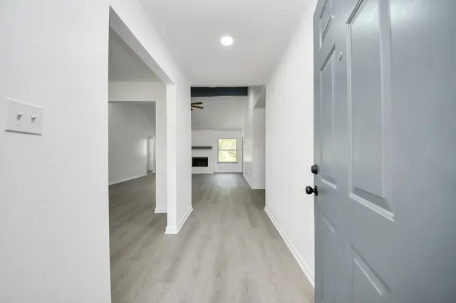 a view of a hallway with wooden floor and a bathroom