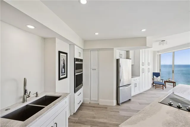 a kitchen with stainless steel appliances kitchen island granite countertop a refrigerator and a sink