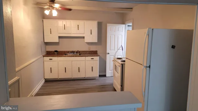 a kitchen with stainless steel appliances a refrigerator a stove a sink and white cabinets