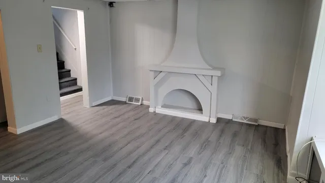 a view of empty room with wooden floor and fireplace