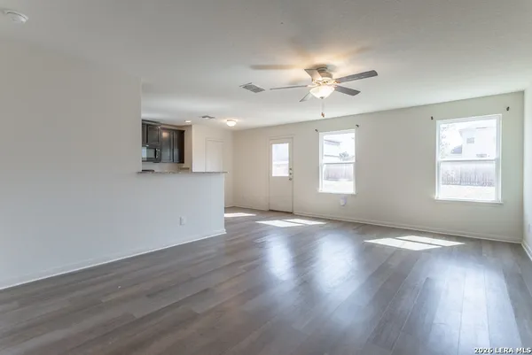 a view of an empty room with a window and wooden floor