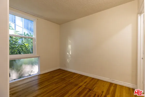 a view of an empty room with wooden floor and a window