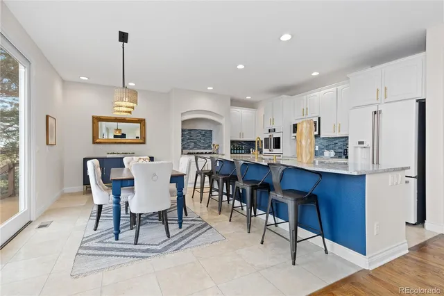 a kitchen with stainless steel appliances granite countertop a table chairs refrigerator a sink and a window