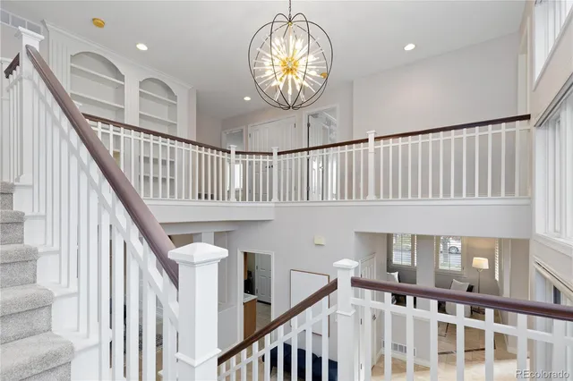 a view of staircase with railing and a chandelier