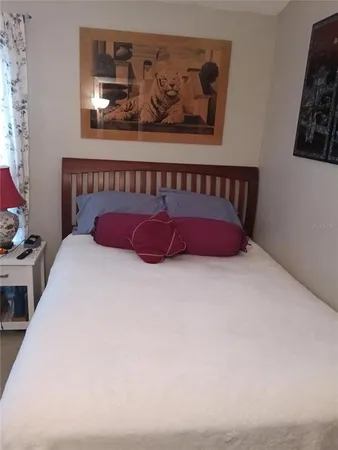 a bed sitting in a bedroom next to a window with painting on the wall