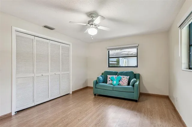 an empty room with wooden floor fan and windows