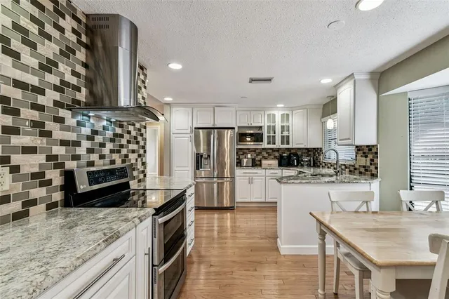 a kitchen with stainless steel appliances granite countertop a sink stove microwave and refrigerator