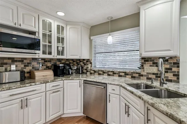 a kitchen with stainless steel appliances granite countertop a sink and a stove