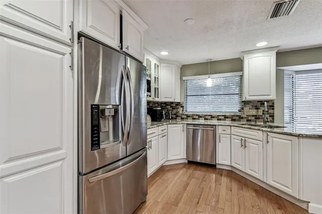 a kitchen with stainless steel appliances kitchen island granite countertop a sink and a white wooden cabinets