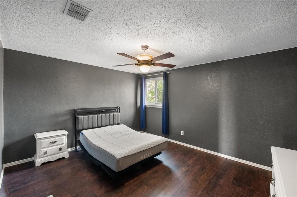 1305 Liverpool Lane Mansfield, TX 76063 - Photo 30 of 40 This room features dark wood flooring, a window with blue curtains, and a ceiling fan with integrated lighting