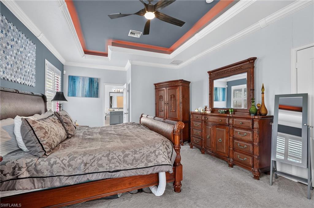 9970 Rookery Circle Estero, FL 33928 - Photo 33 of 50 Tray ceiling with crown molding, ceiling fan, carpet flooring, plantation shutters, and recessed lighting