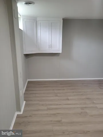 a view of an empty room with wooden floor and cabinets