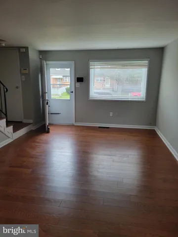 an empty room with wooden floor cabinet and windows