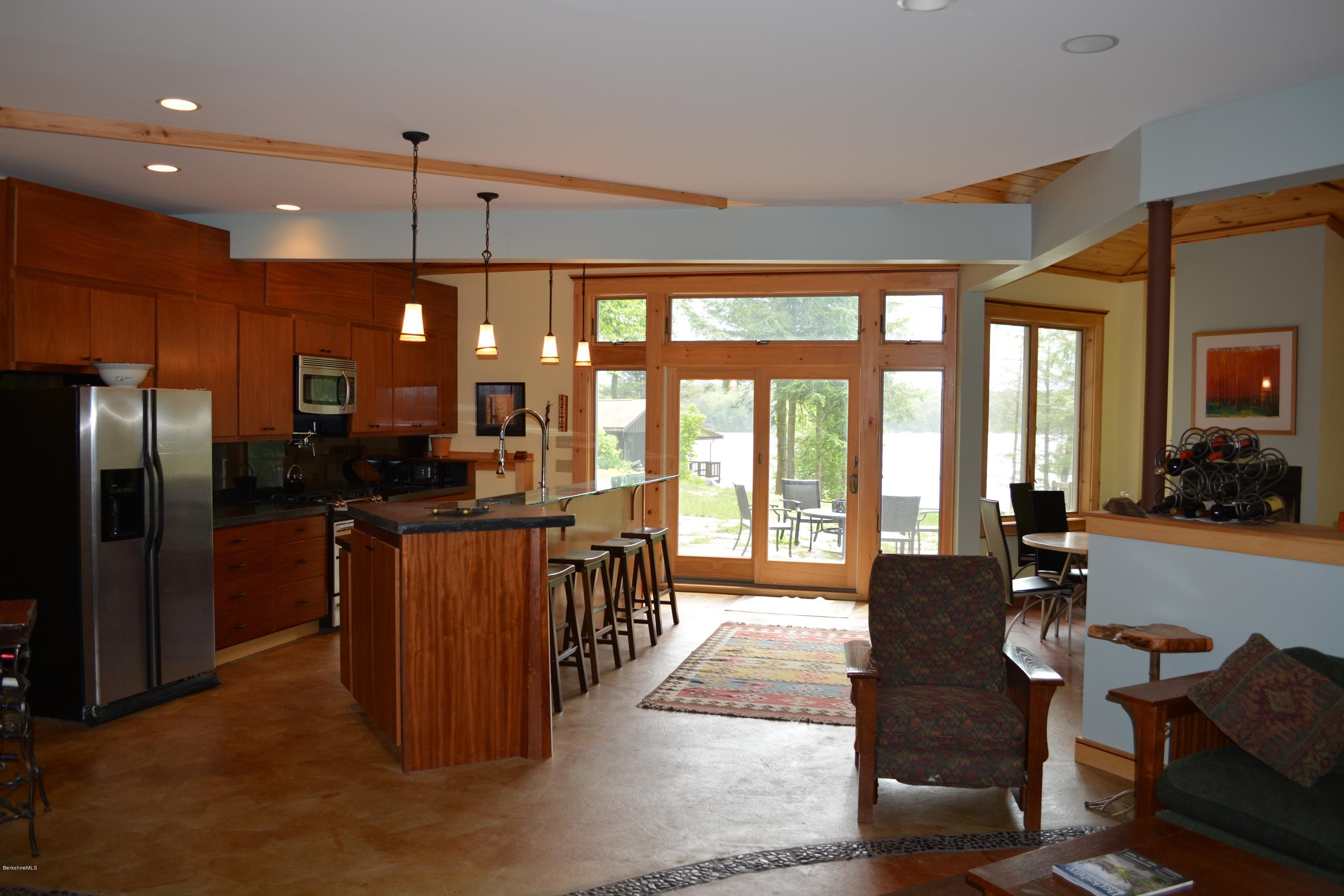 317 Pine Road Otis, MA 01029 - Photo 3 of 27 a kitchen with stainless steel appliances kitchen island granite countertop a refrigerator a stove a sink a dining table and chairs with wooden floor