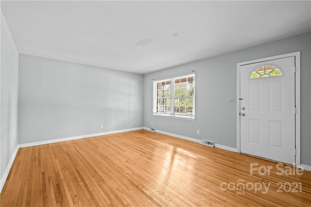 6833 Idlewild Road Charlotte, NC 28212 - Photo 7 of 24 a view of empty room with window and wooden floor