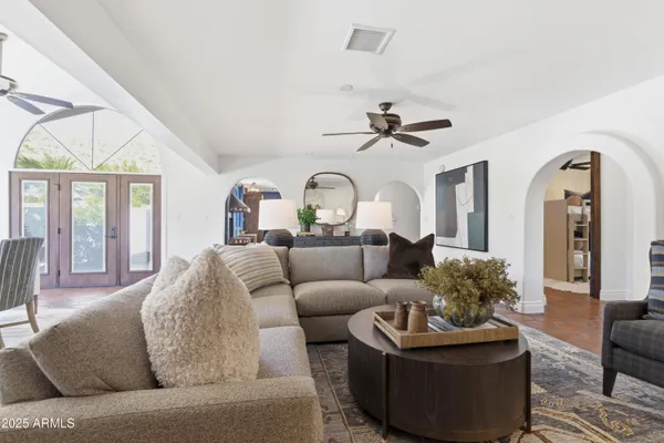 a living room with furniture a ceiling fan and a large window