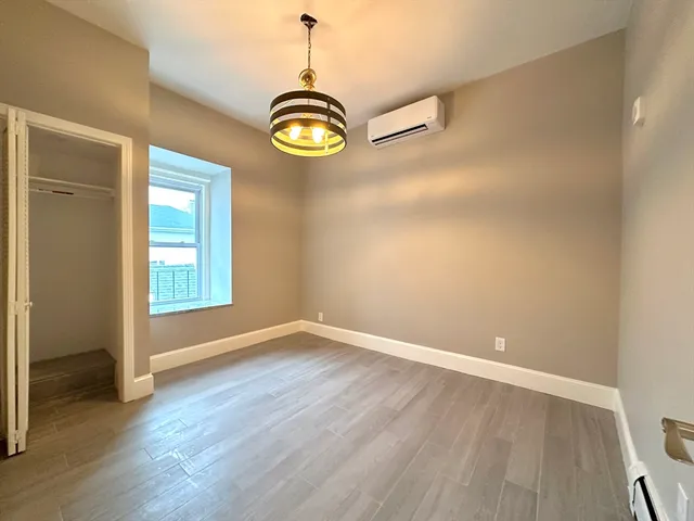 a view of empty room with wooden floor and window