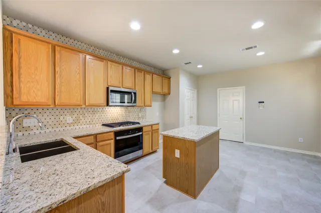 a kitchen with stainless steel appliances granite countertop a sink stove and refrigerator
