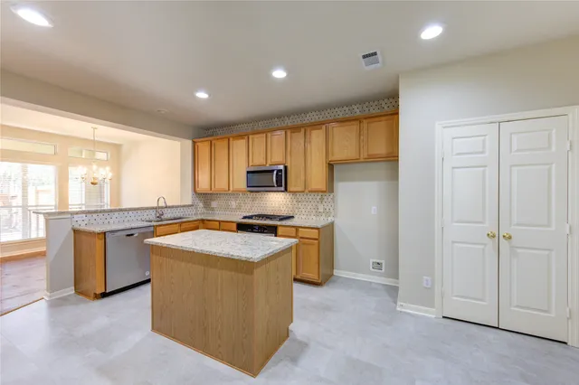 a kitchen with stainless steel appliances granite countertop a stove a sink a refrigerator and cabinets